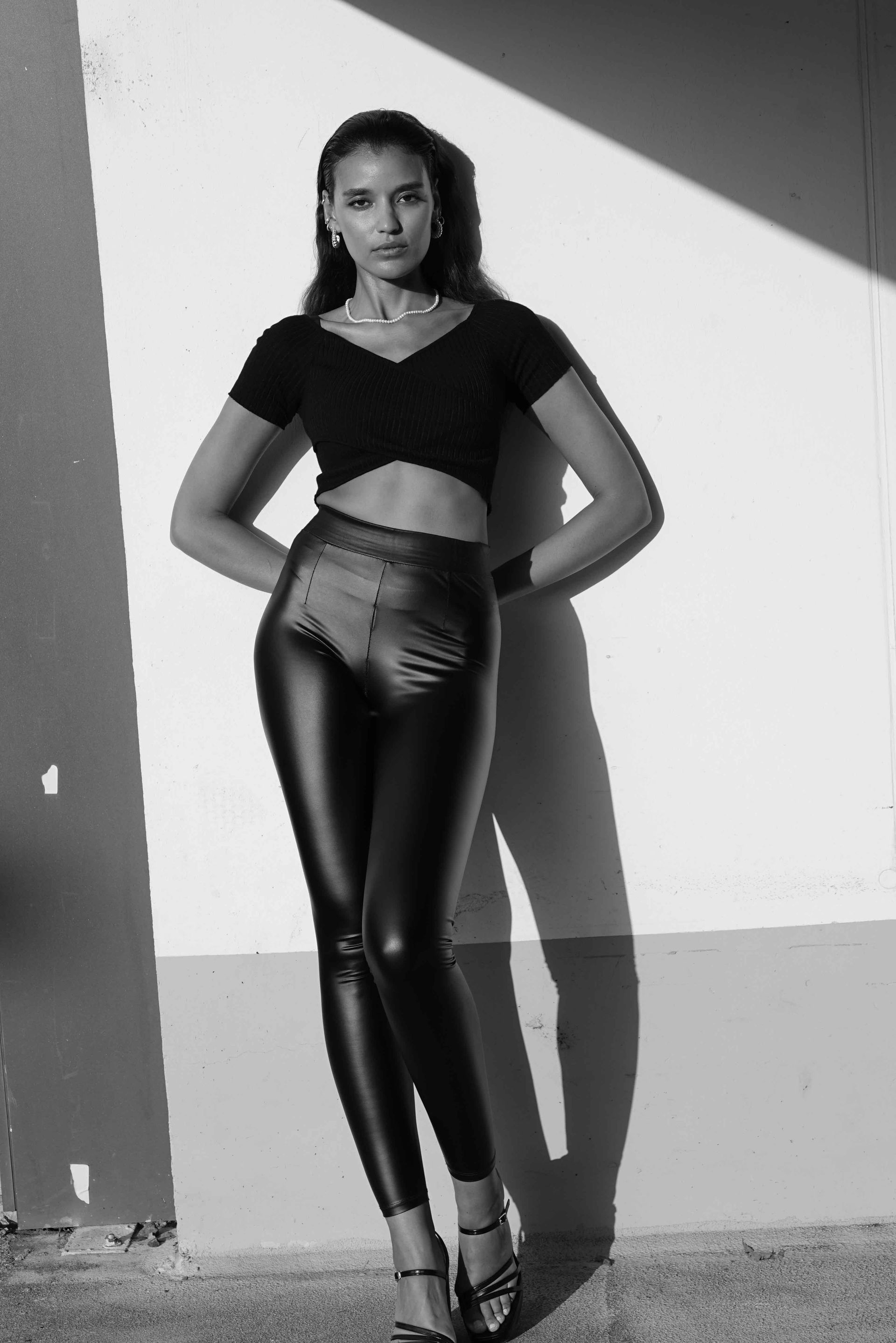 Ein Schwarzweißfoto einer Frau in Lederhosen und bauchfreiem Top.