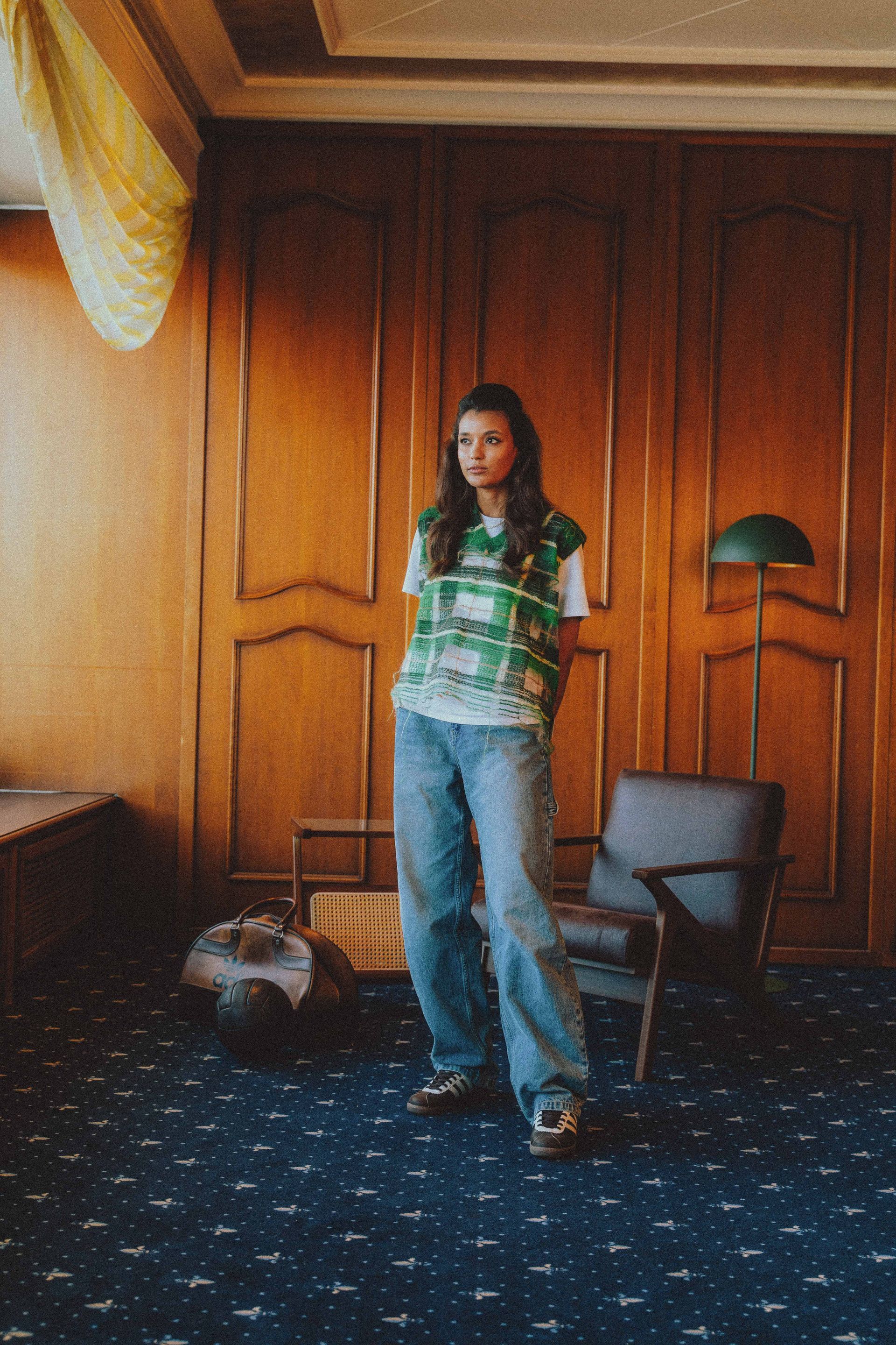 Eine Frau steht in einem Raum mit einem Stuhl und einer Lampe.