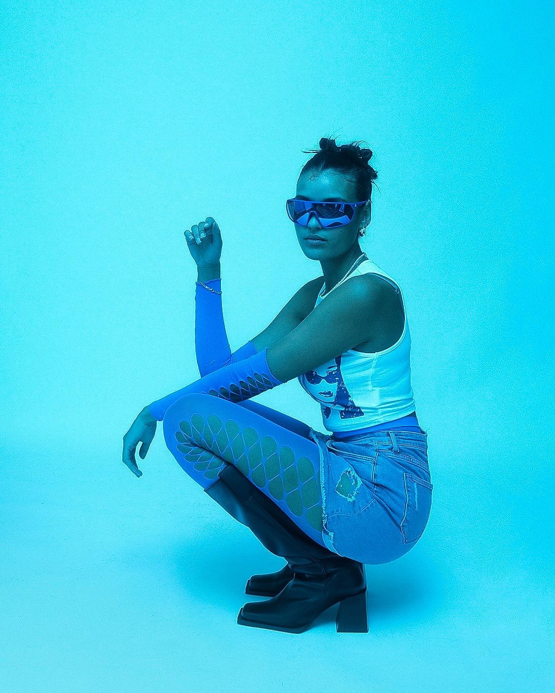 Eine Frau hockt vor einem blauen Hintergrund.