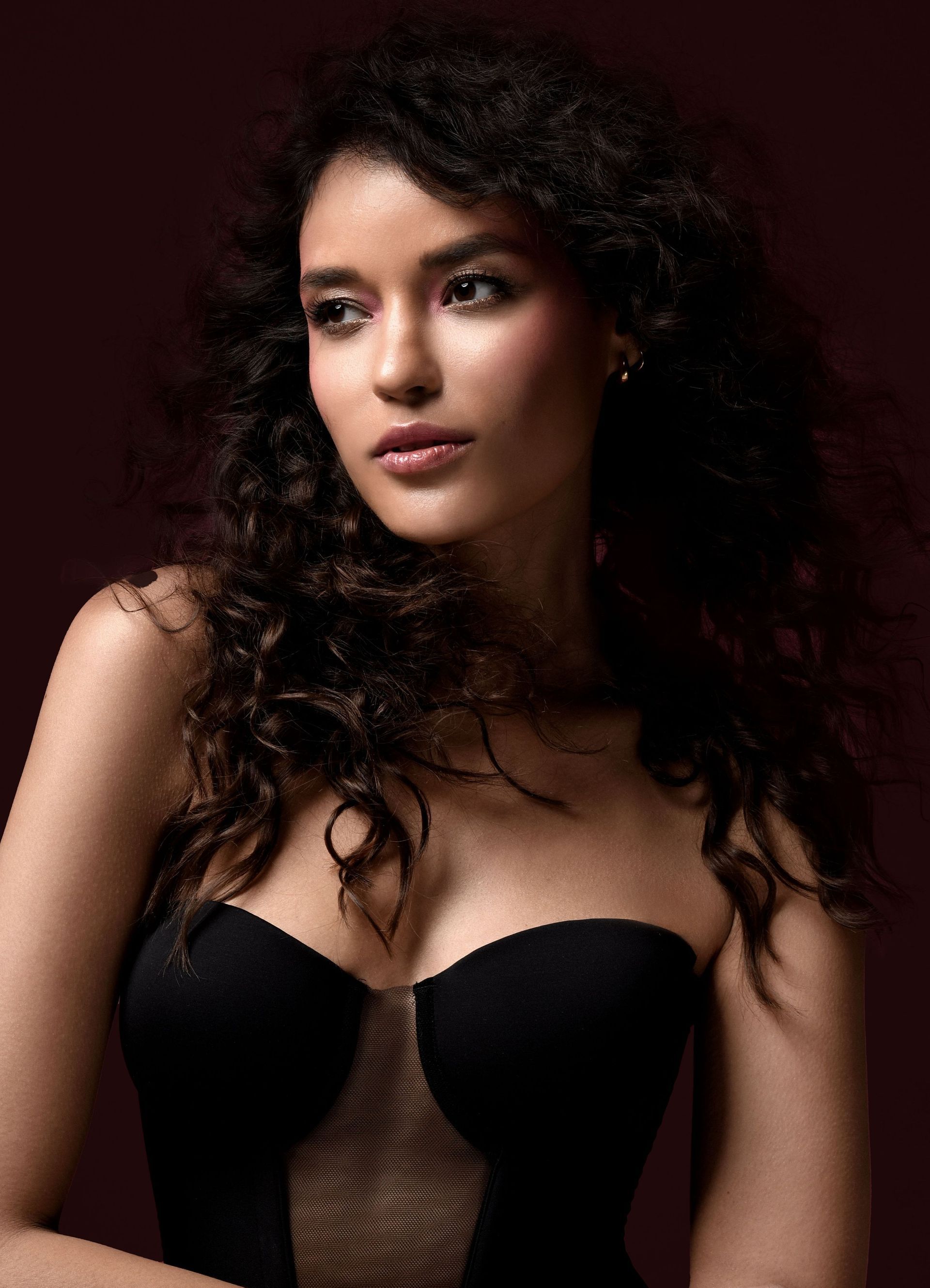 Eine Frau mit lockigem Haar trägt ein schwarzes trägerloses Kleid.