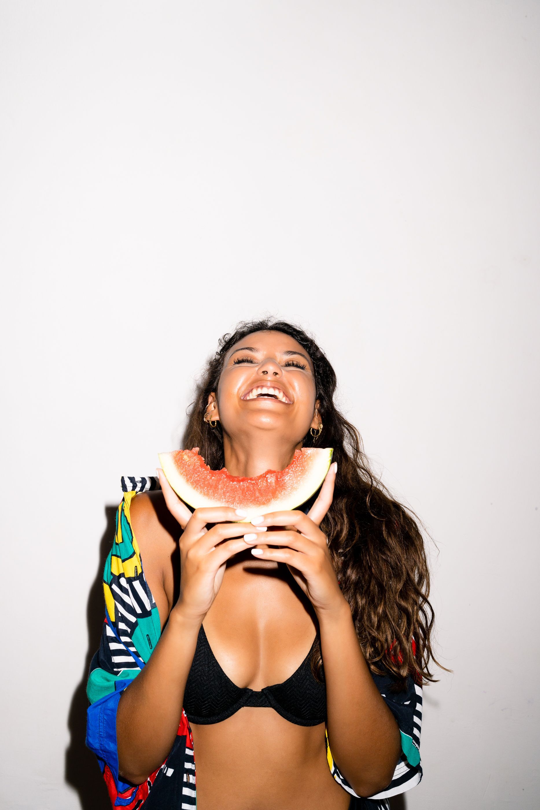 Eine Frau im Bikini hält ein Stück Wassermelone.