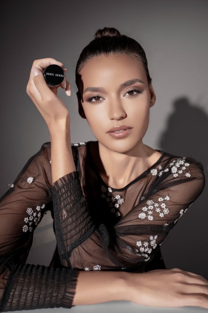 Eine Frau in einem schwarzen Kleid hält einen schwarzen Gegenstand in der Hand.