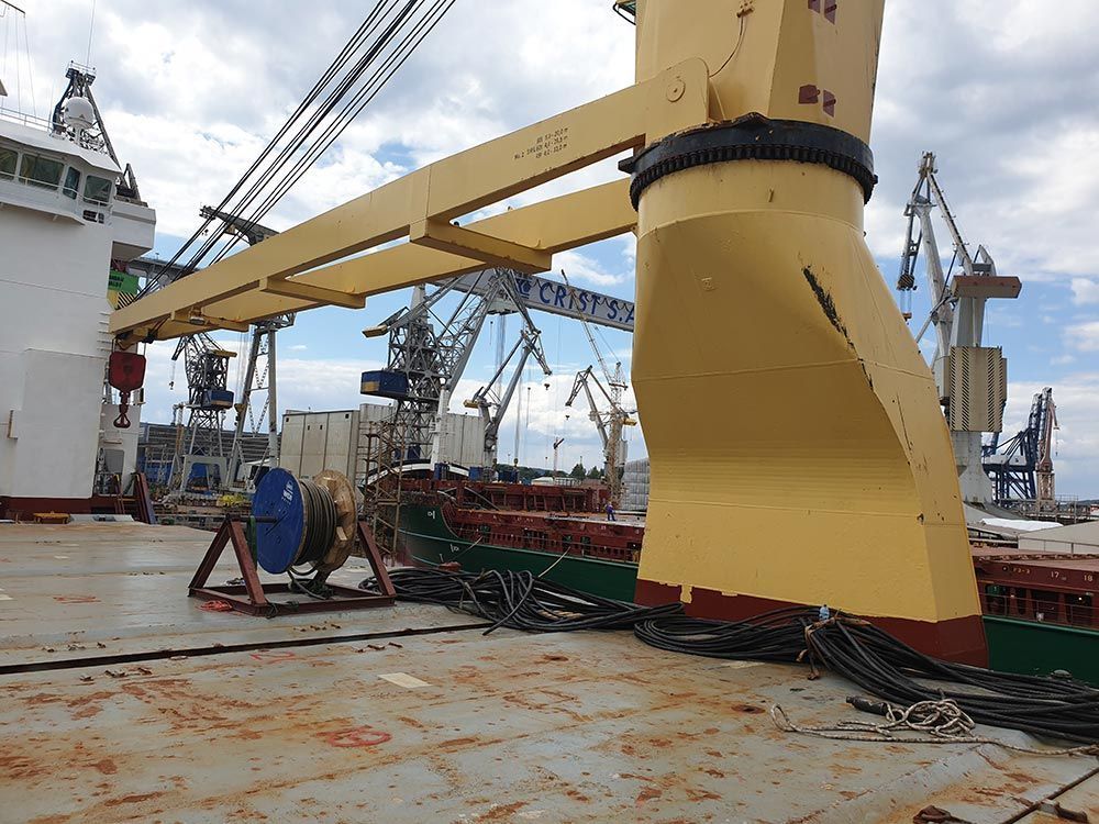 Ein großer gelber Kran steht auf dem Deck eines großen Schiffs.