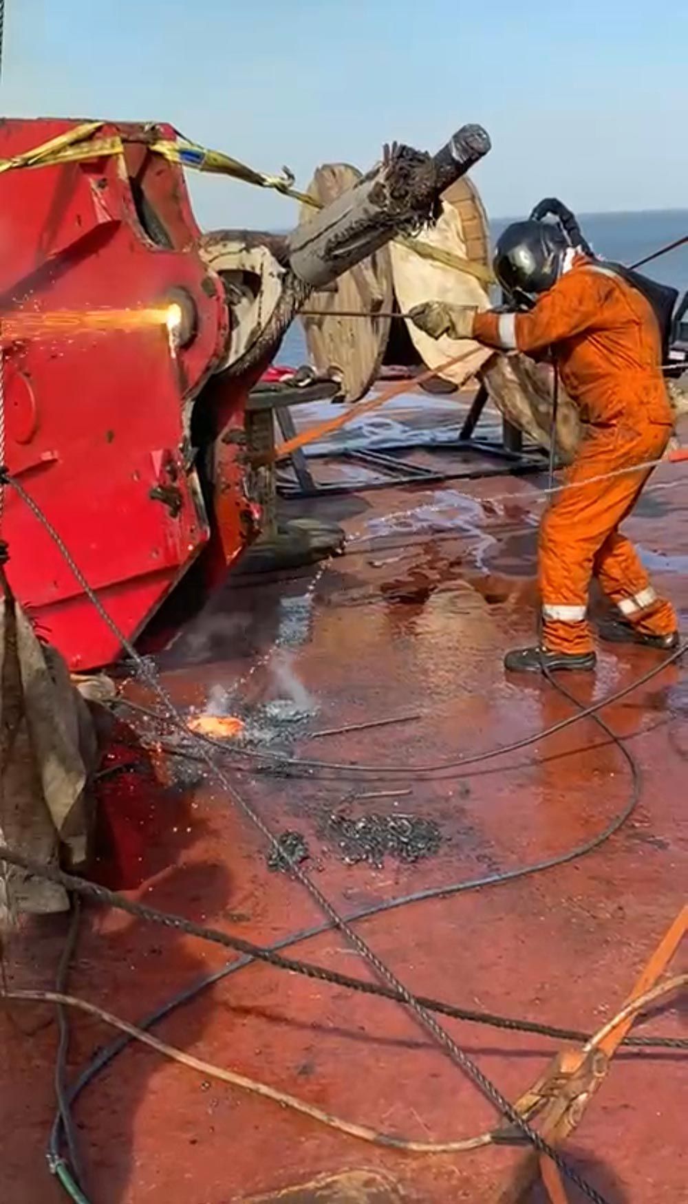 Ein Mann schweißt ein Stück Metall an einem Boot.