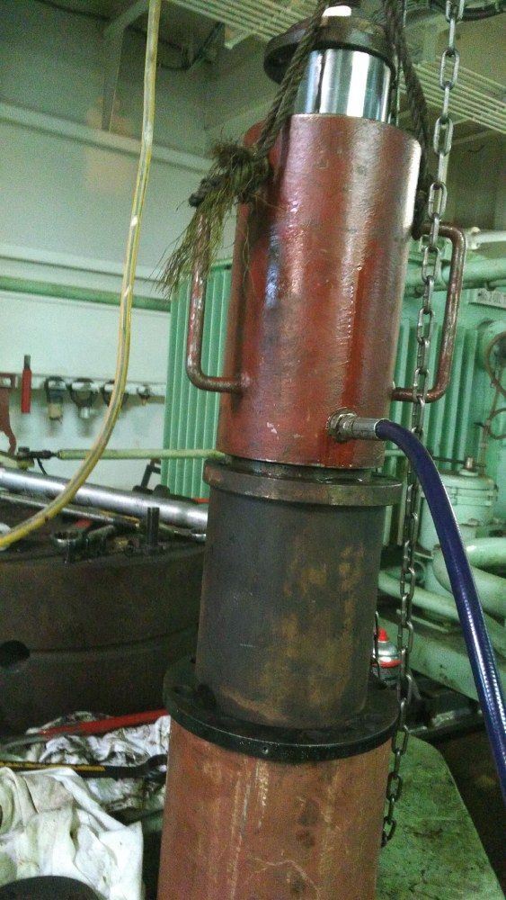 In einer Fabrik wird ein Hydraulikzylinder mithilfe von Ketten angehoben.