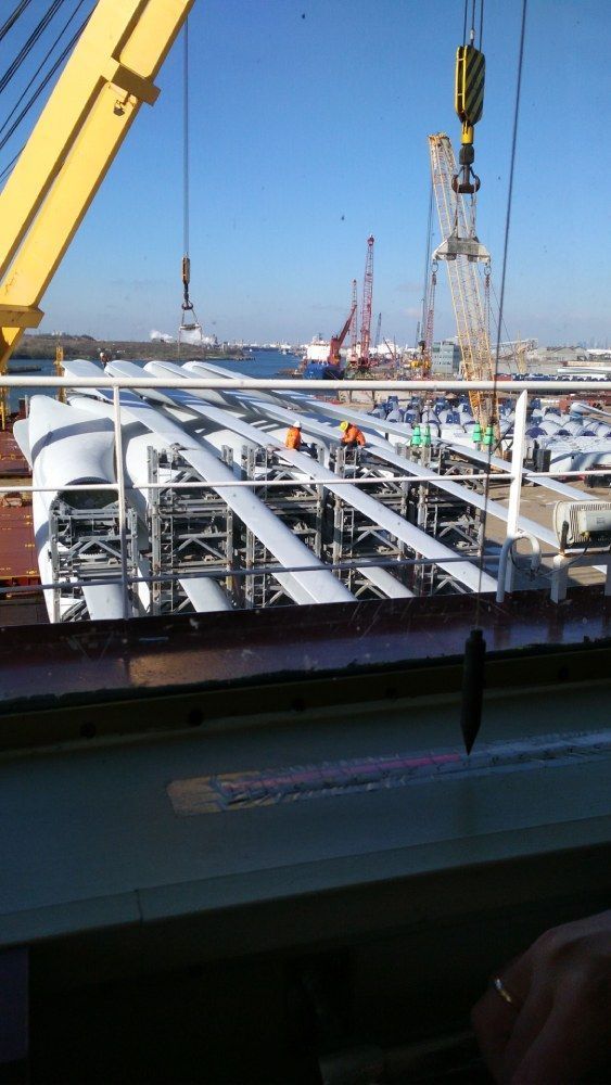 Ein großer gelber Kran wird zum Anheben eines großen Rohrs verwendet