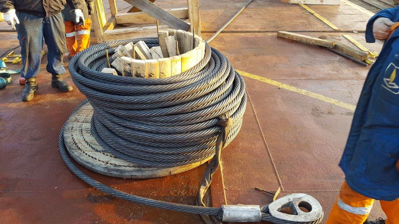 Eine Person steht neben einer großen Seilspule.