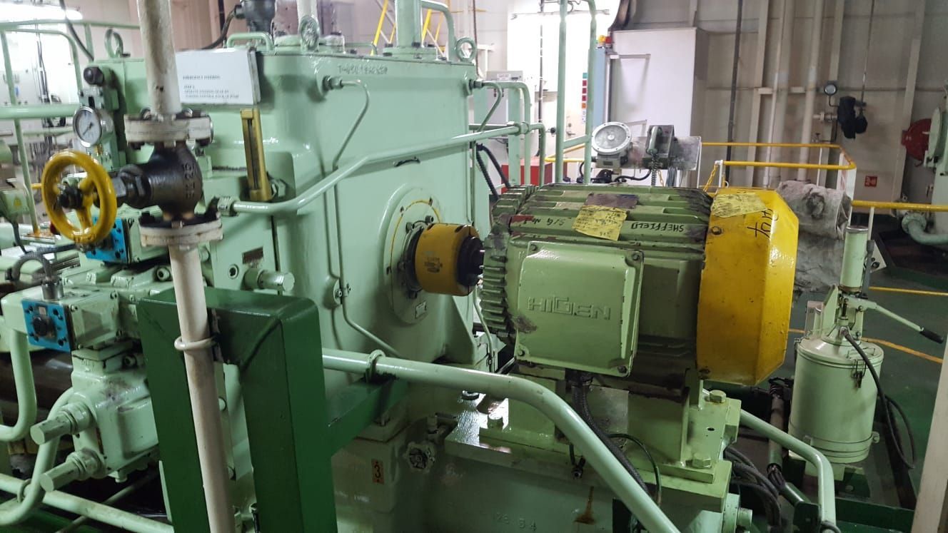 In einem Raum mit vielen Rohren steht eine große Maschine.