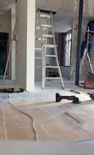 Un hombre está de pie en una escalera en una habitación en construcción.