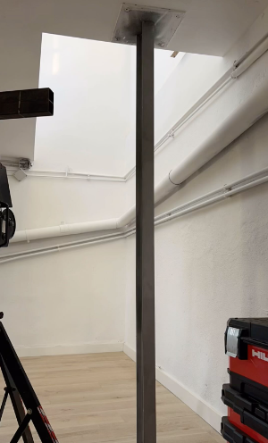 Una cámara está colocada sobre un trípode en una habitación al lado de un poste.