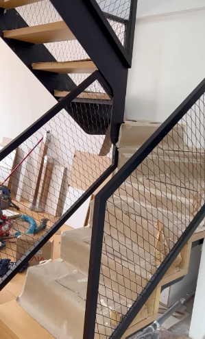 Se está construyendo una escalera con barandilla negra en una casa.