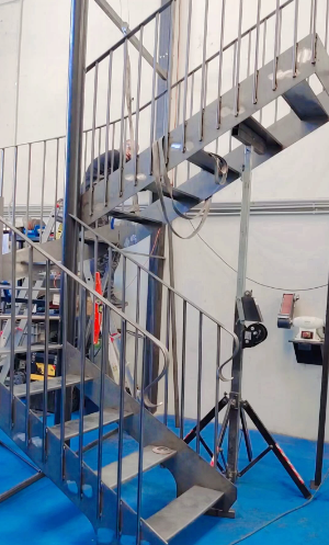 Una escalera de caracol de metal reposa sobre un suelo azul en una habitación.