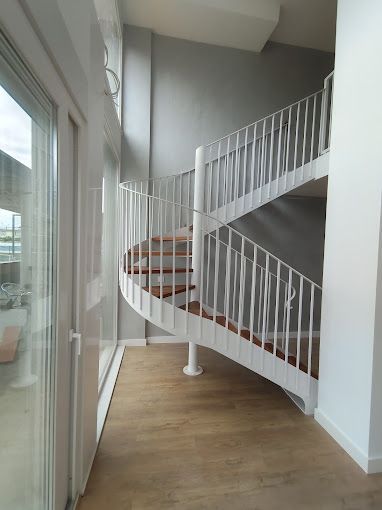 Una escalera de caracol con escalones de madera y barandilla blanca.