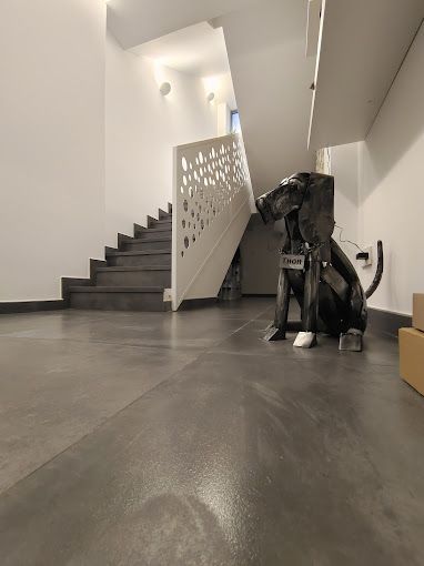 Una estatua de un perro está sentada en un pasillo al lado de una escalera.
