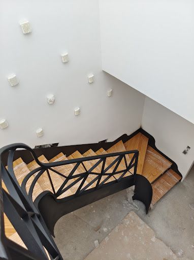 Las escaleras son de madera y metal y tienen una barandilla negra.