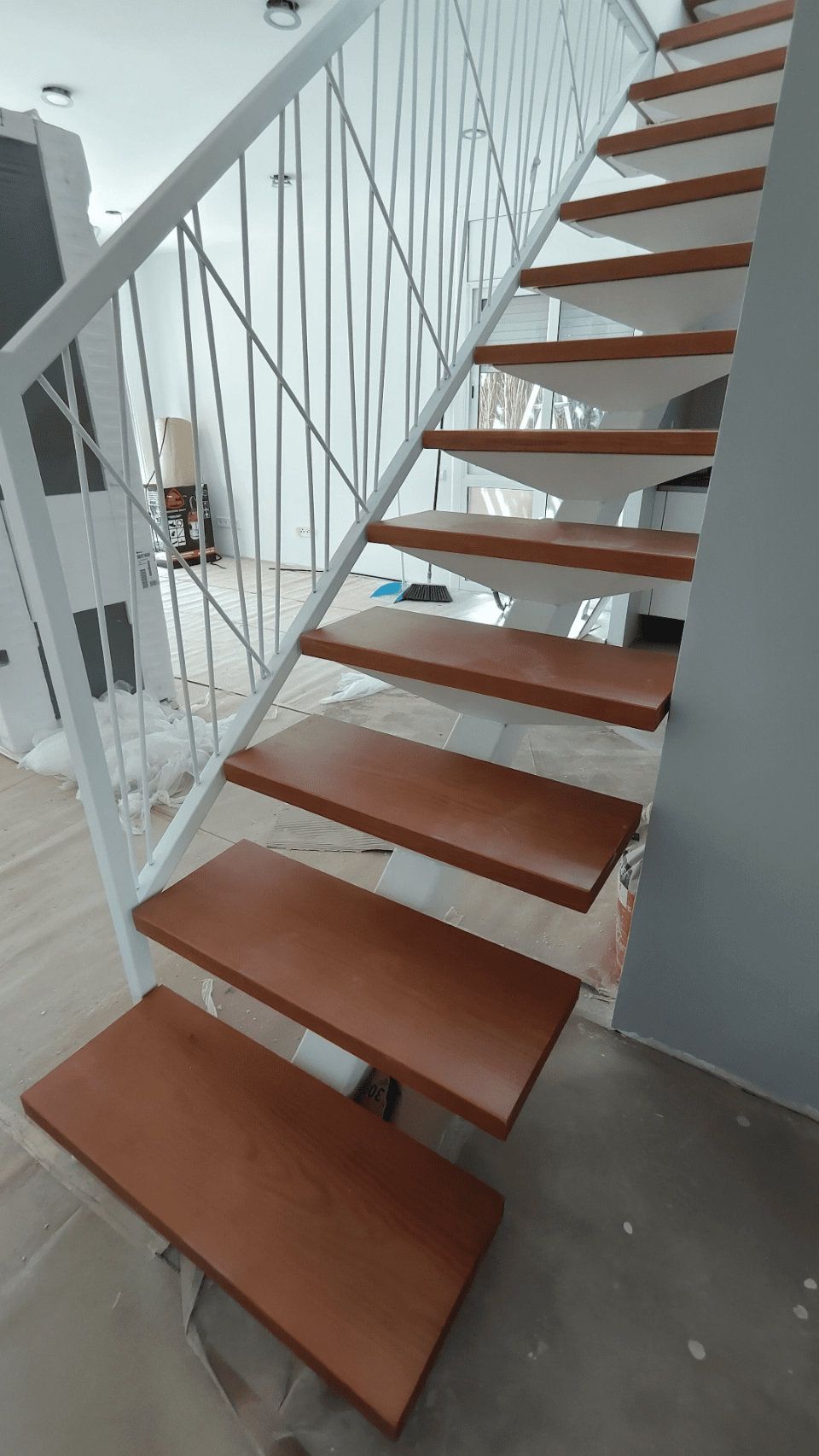 Una escalera de madera con barandilla blanca en una sala de estar.