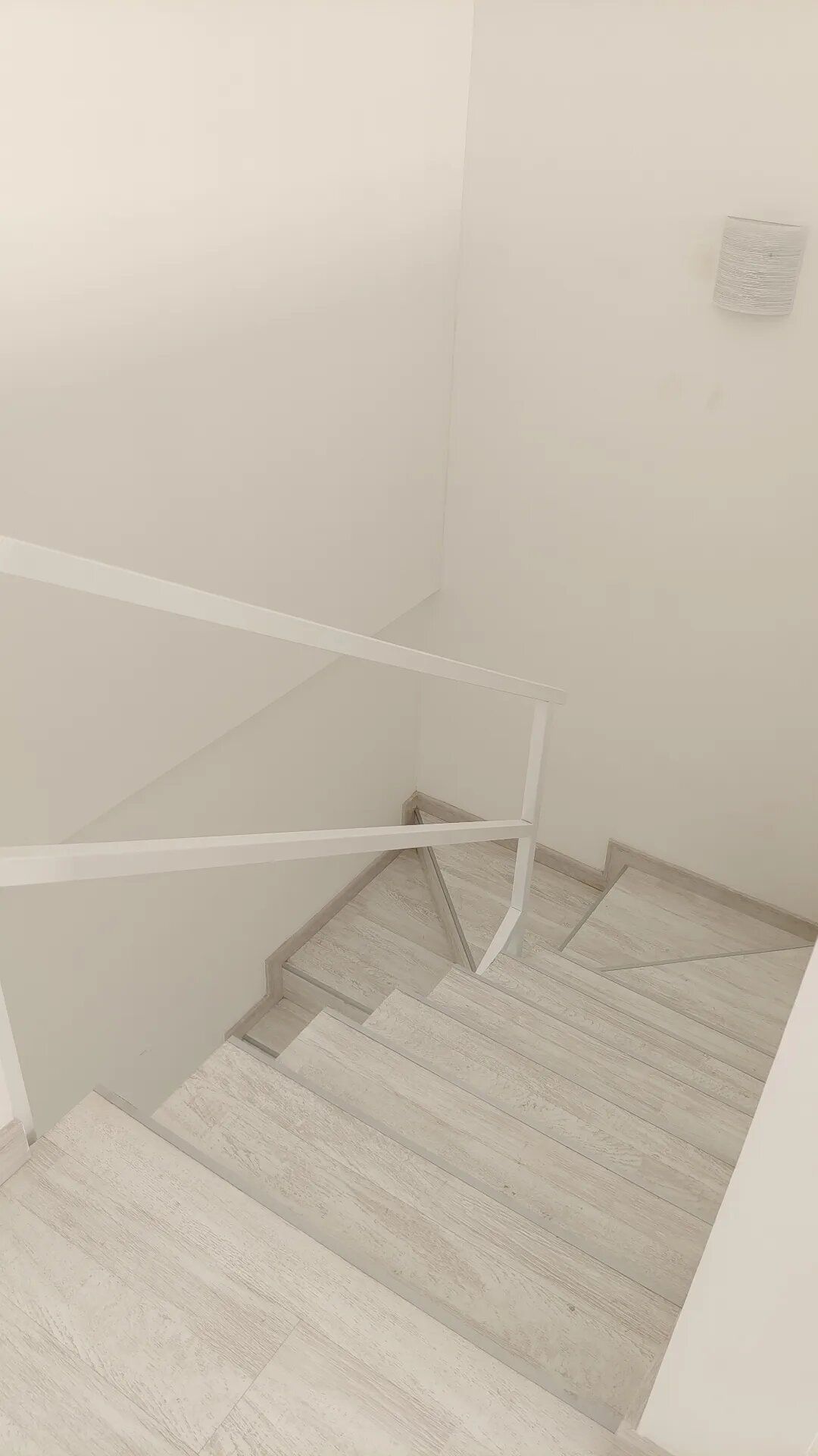 Una escalera blanca con una barandilla blanca y una pared blanca.