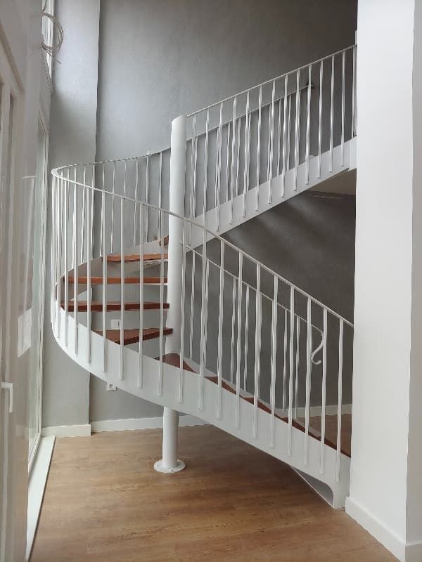Una escalera de caracol con barandilla blanca y escalones de madera.