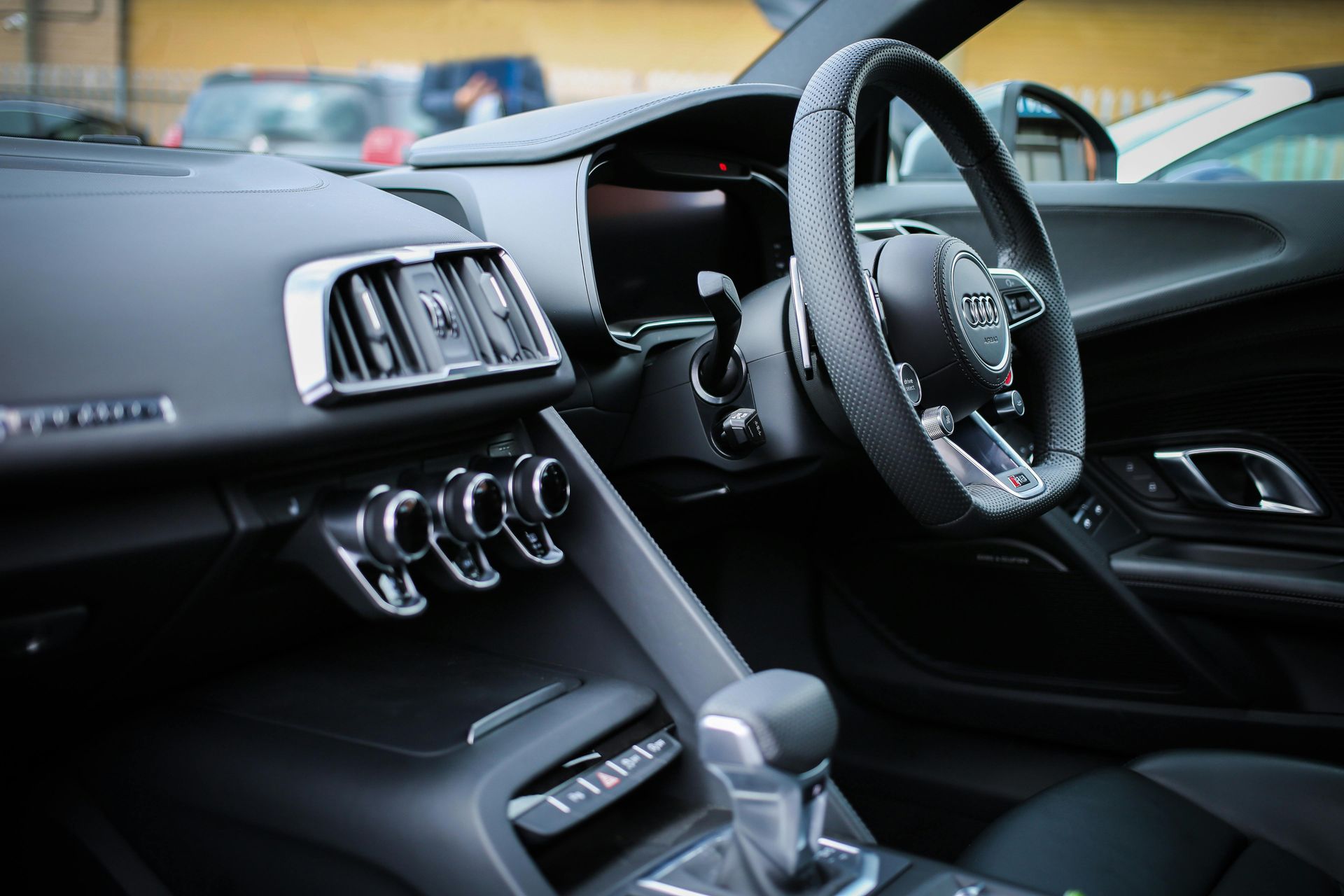 Interior del Audi R8 en color negro, con tablero, volante y palanca de cambios visibles.