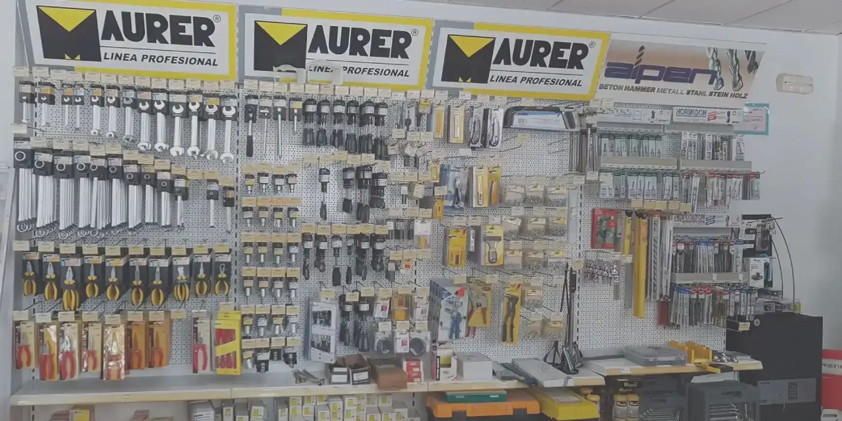 Una pared llena de muchas herramientas y un cartel que dice aurer