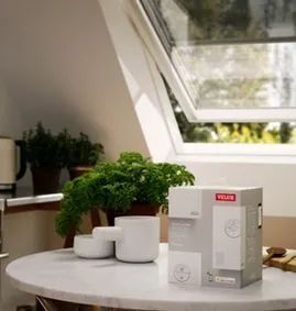 Una mesa blanca con una caja encima y una ventana al fondo.