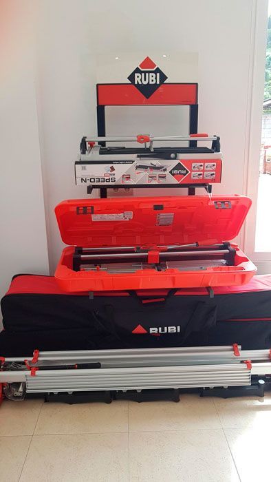 Una exposición de cortadores de baldosas Rubi y estuches en una habitación.
