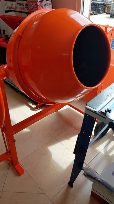 Una hormigonera está colocada sobre un suelo de baldosas al lado de una mesa.