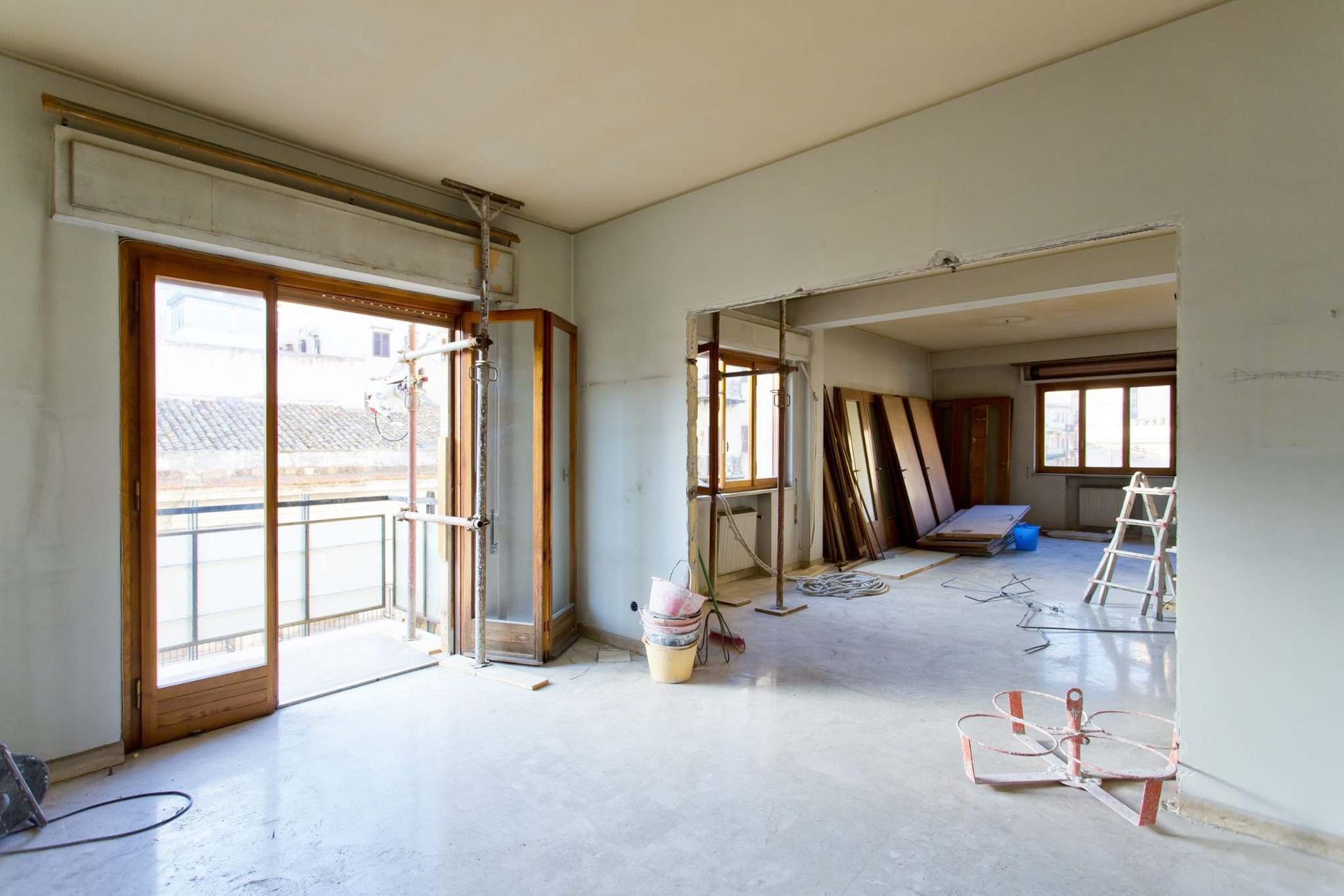 Habitación luminosa sin terminar con puertas corredizas de vidrio, estructura a la vista.