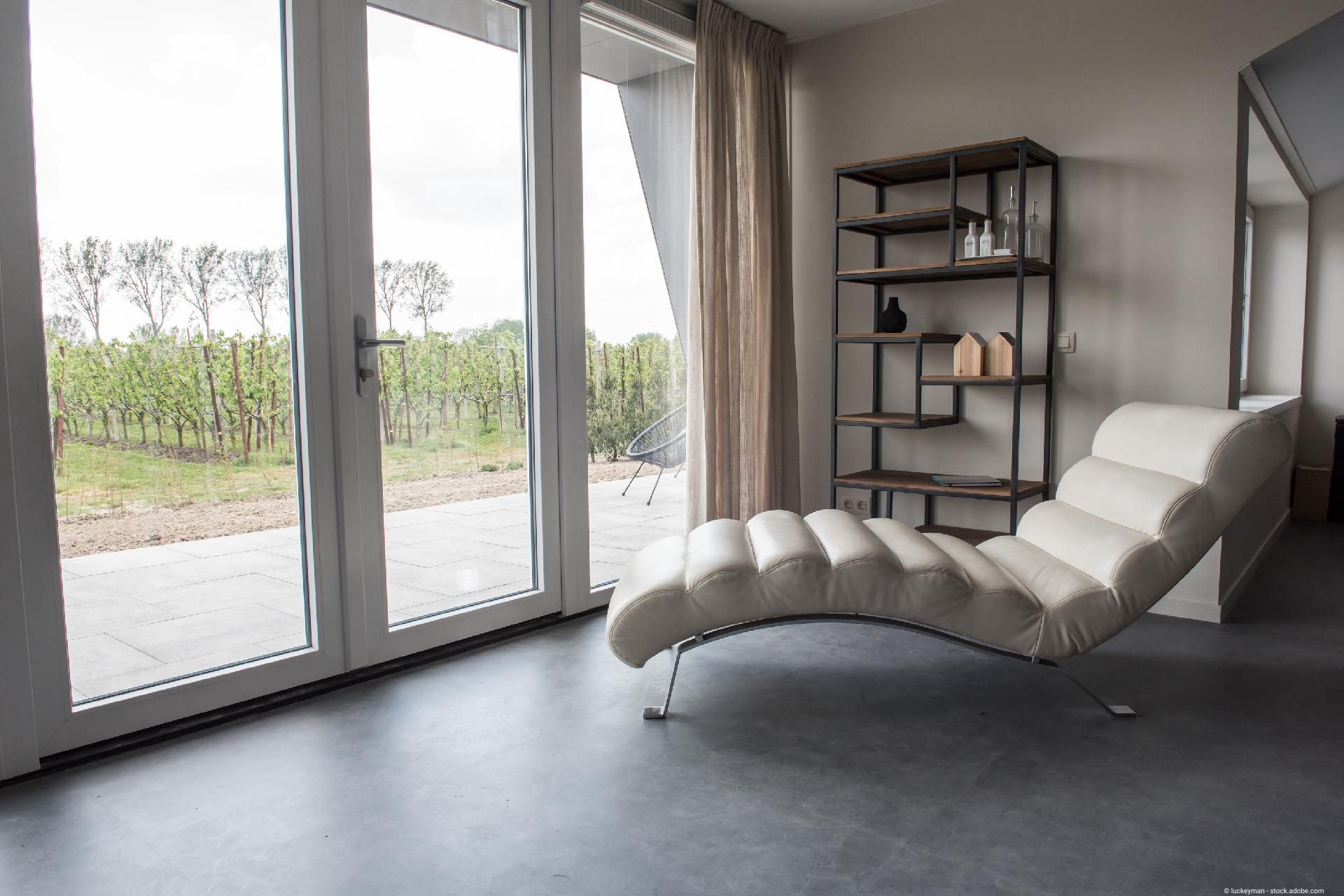 Helles, minimalistisches Interieur mit einer Topfpflanze, eleganter Holzvertäfelung und Fischgrätparkett. Natürliches Licht durchflutet den Raum.