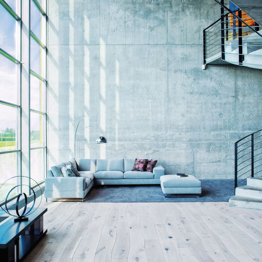 Modernes Wohnzimmer mit grünem Sofa, weißen Möbeln, einem verglasten Kamin und großen Fenstern mit schwarzen Jalousien.