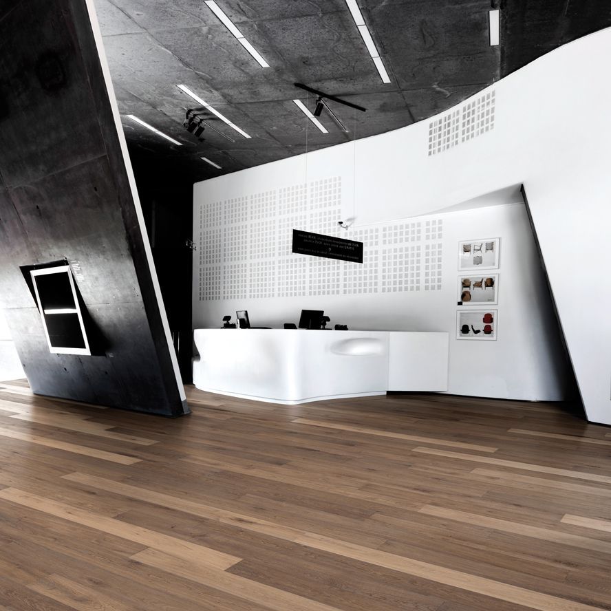 Dunkles Parkett in einem großen Raum mit organischen Formen an einem Tresen und einer Wand