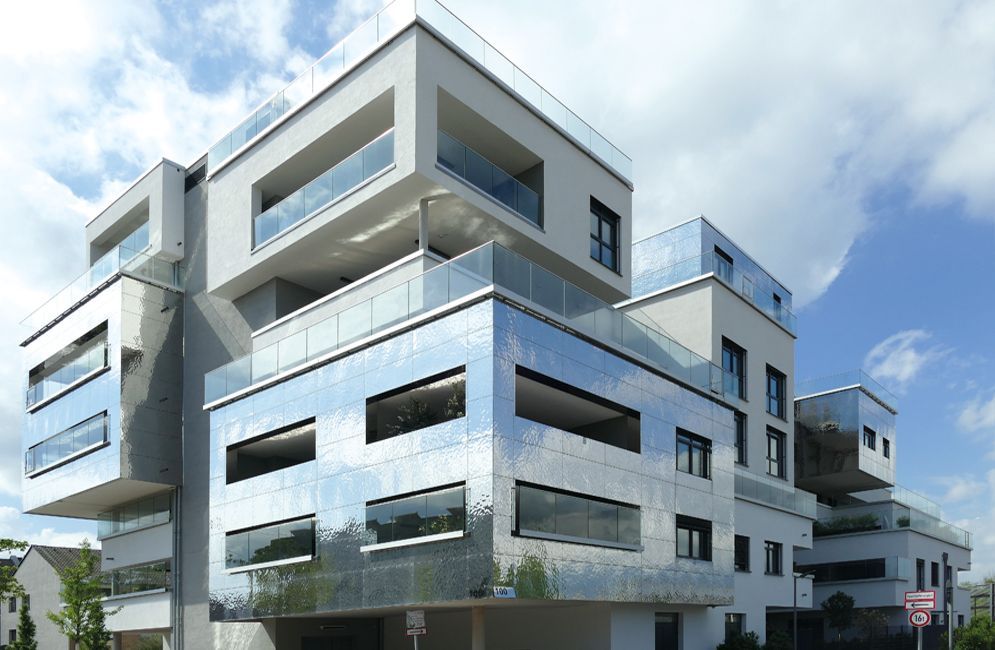 Moderne Büroräume mit Holzakzenten, geräumigen Schreibtischen, Computern und großen Fenstern, die natürliches Licht hereinlassen. 