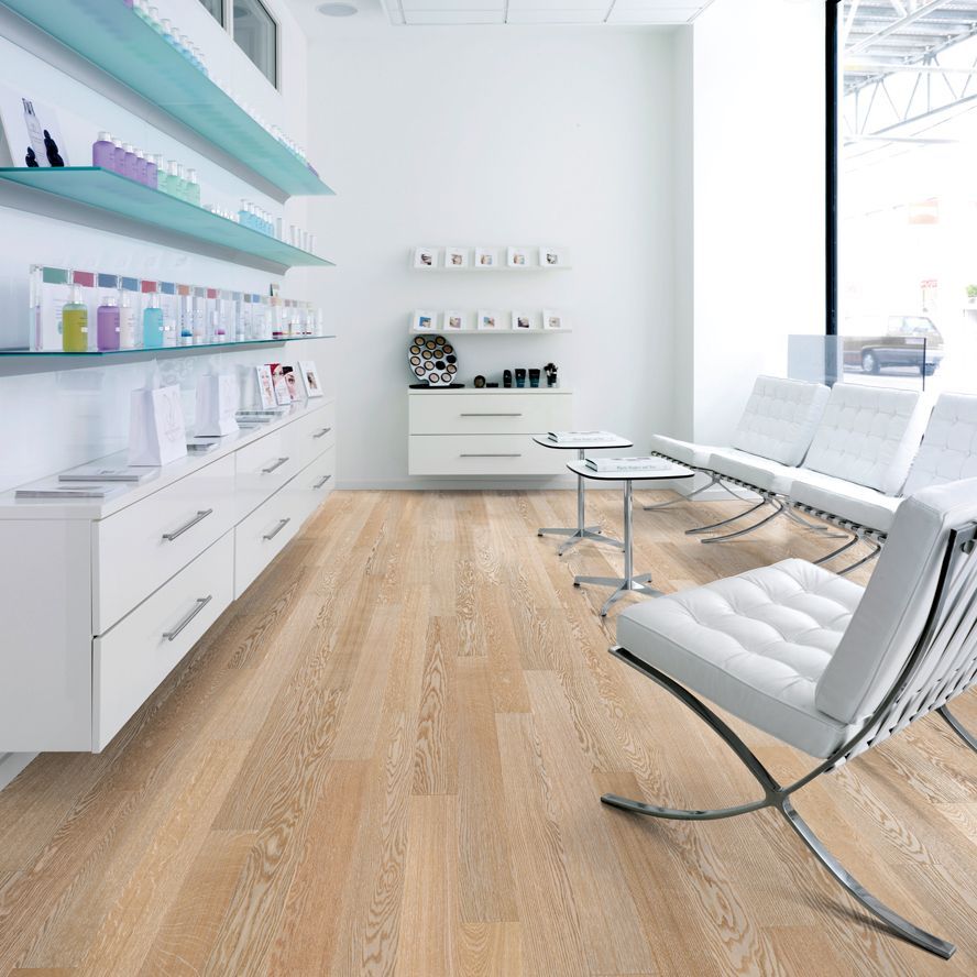 Eine Person, die einen Gummihammer und einen Abstandshalter benutzt, um einen Holzboden zu verlegen, wobei der Klebstoff gleichmäßig auf dem Unterboden verteilt wird.