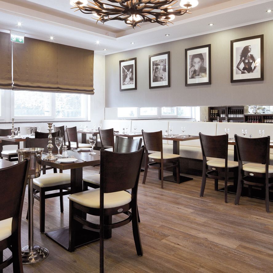 Eine Person verlegt einen Holzfußboden auf einem Kleber, der auf einer Betonfläche aufgetragen wurde, und hat Werkzeuge und Zubehör dabei.