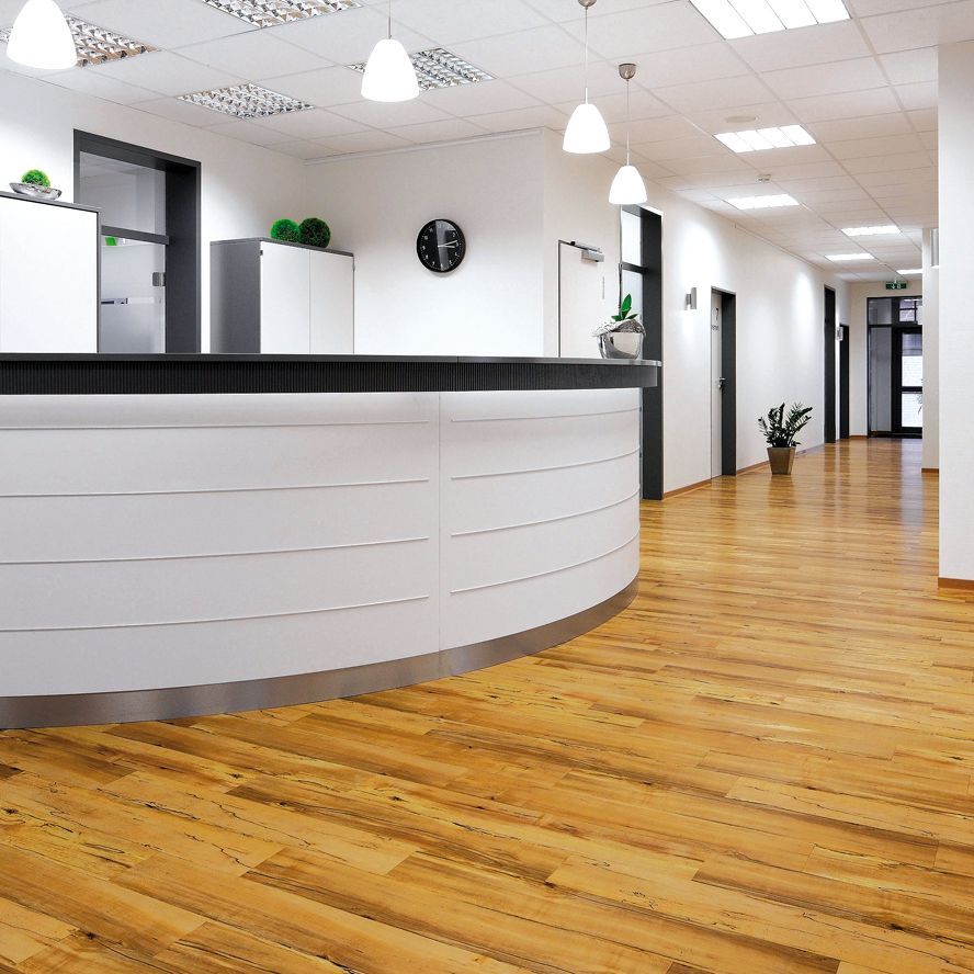 Ein Arbeiter trägt Klebstoff auf den Boden auf, während er die Verlegung von Holzdielen bei einer Hausrenovierung vorbereitet.