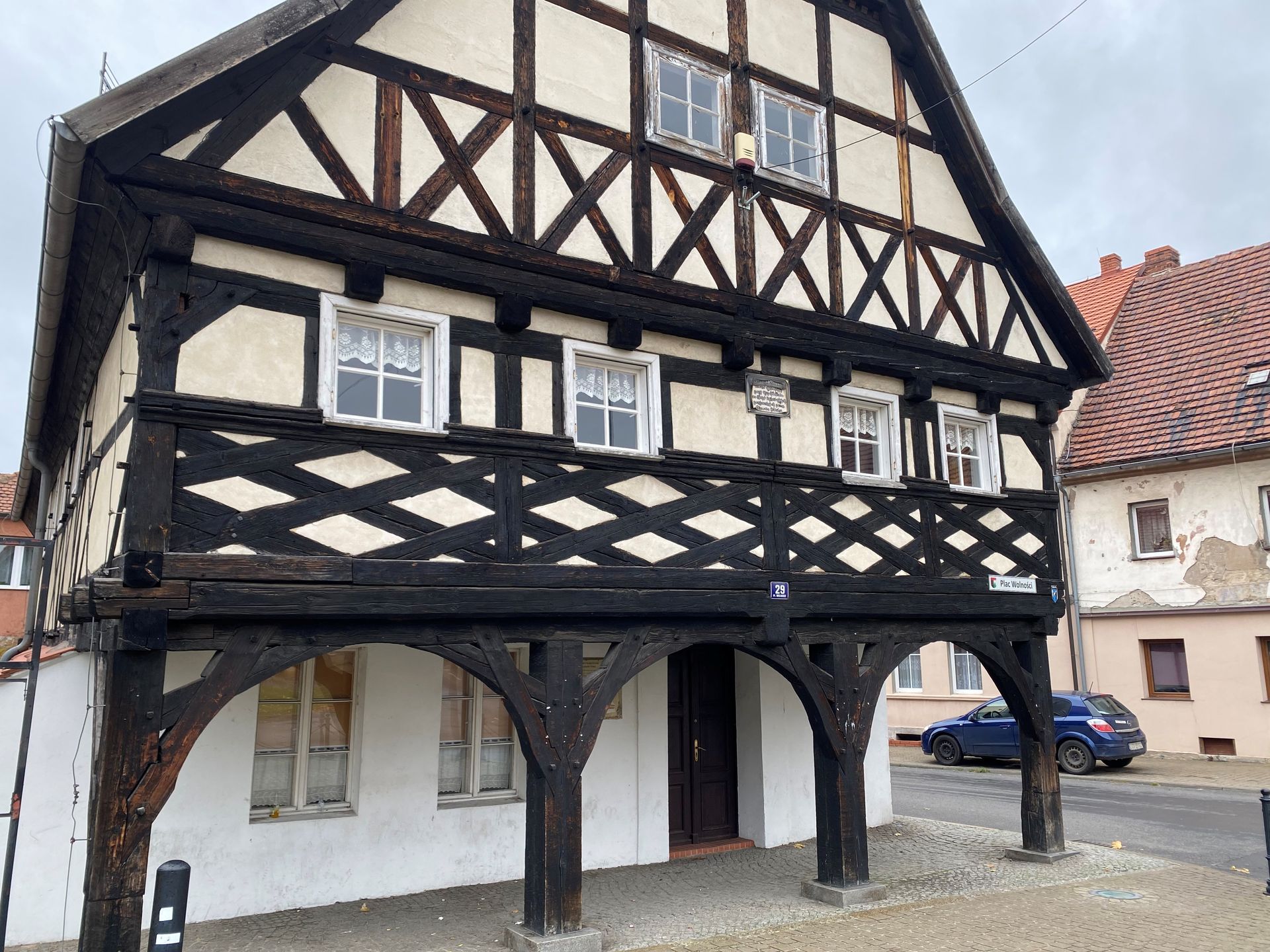 Fachwerkhaus mit dunklen Balken, weißen Wänden und einem überdachten Gang.