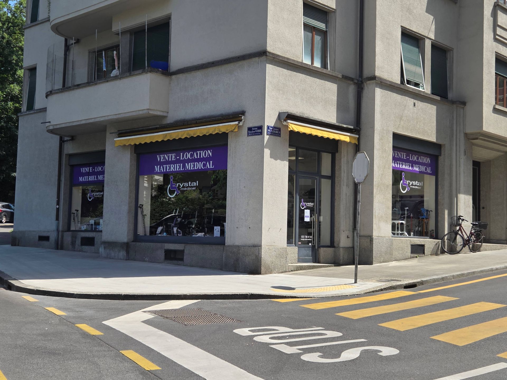 Commerces d'angle dans une rue de la ville, avec des enseignes violettes et un passage piéton devant.