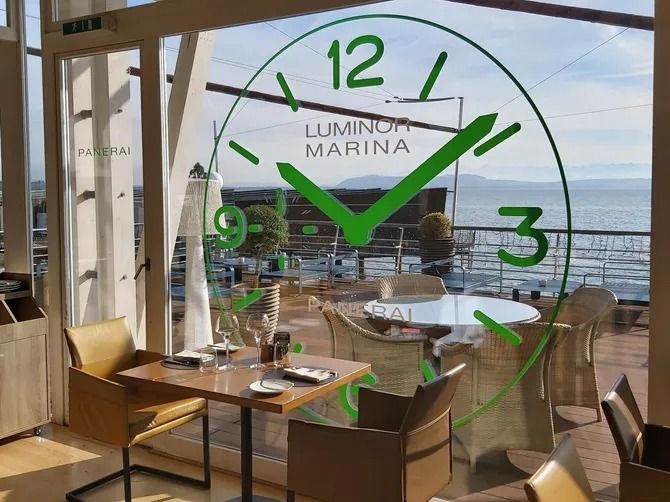 Salle de restaurant avec vue sur l'océan et vue sur la mer, près d'une fenêtre ornée d'une grande horloge verte.