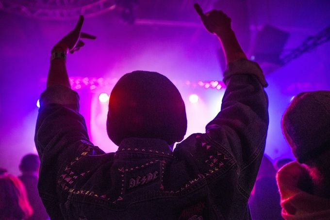 Una persona con los brazos en el aire en un concierto.