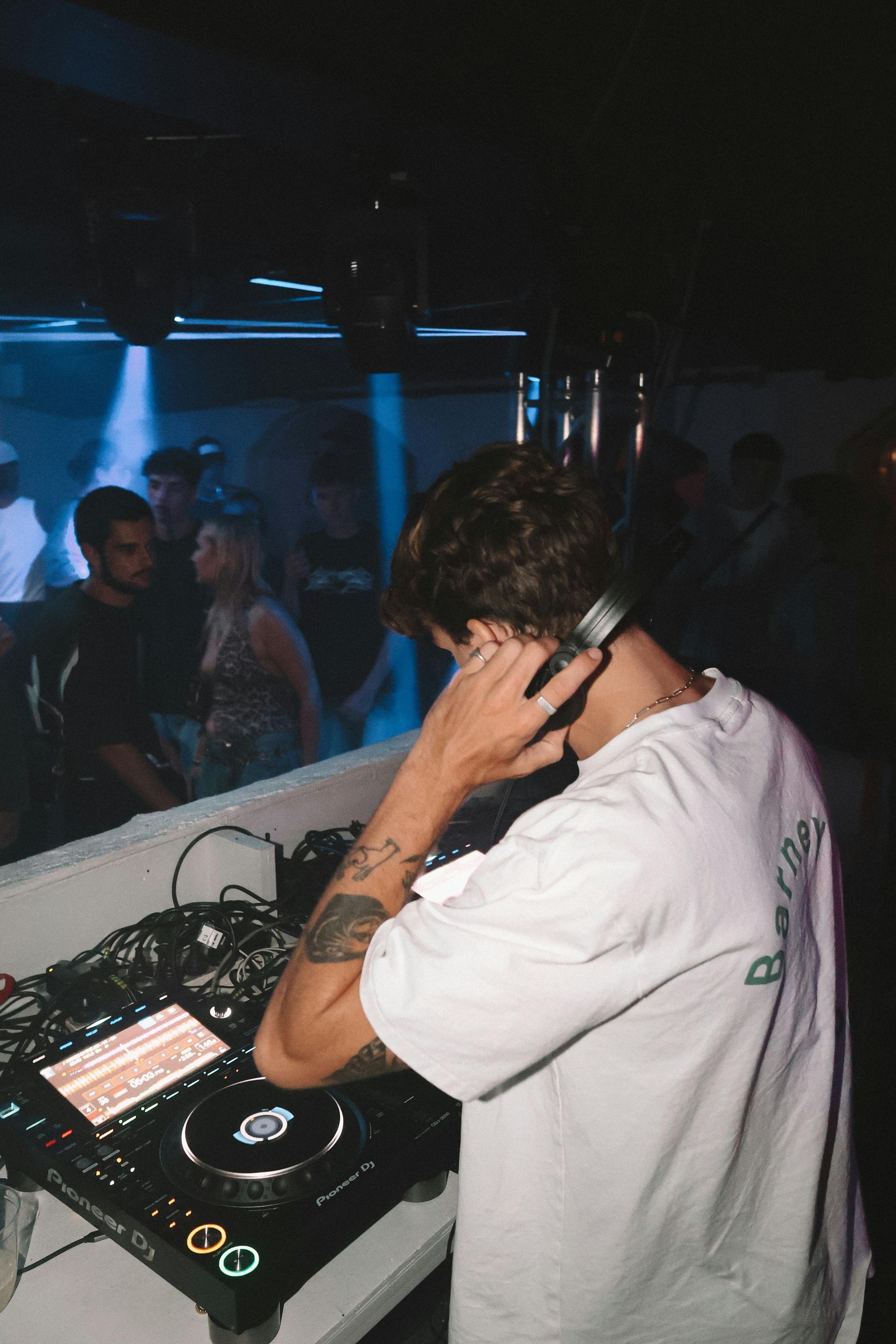 Un hombre usa auriculares mientras reproduce música en un club.