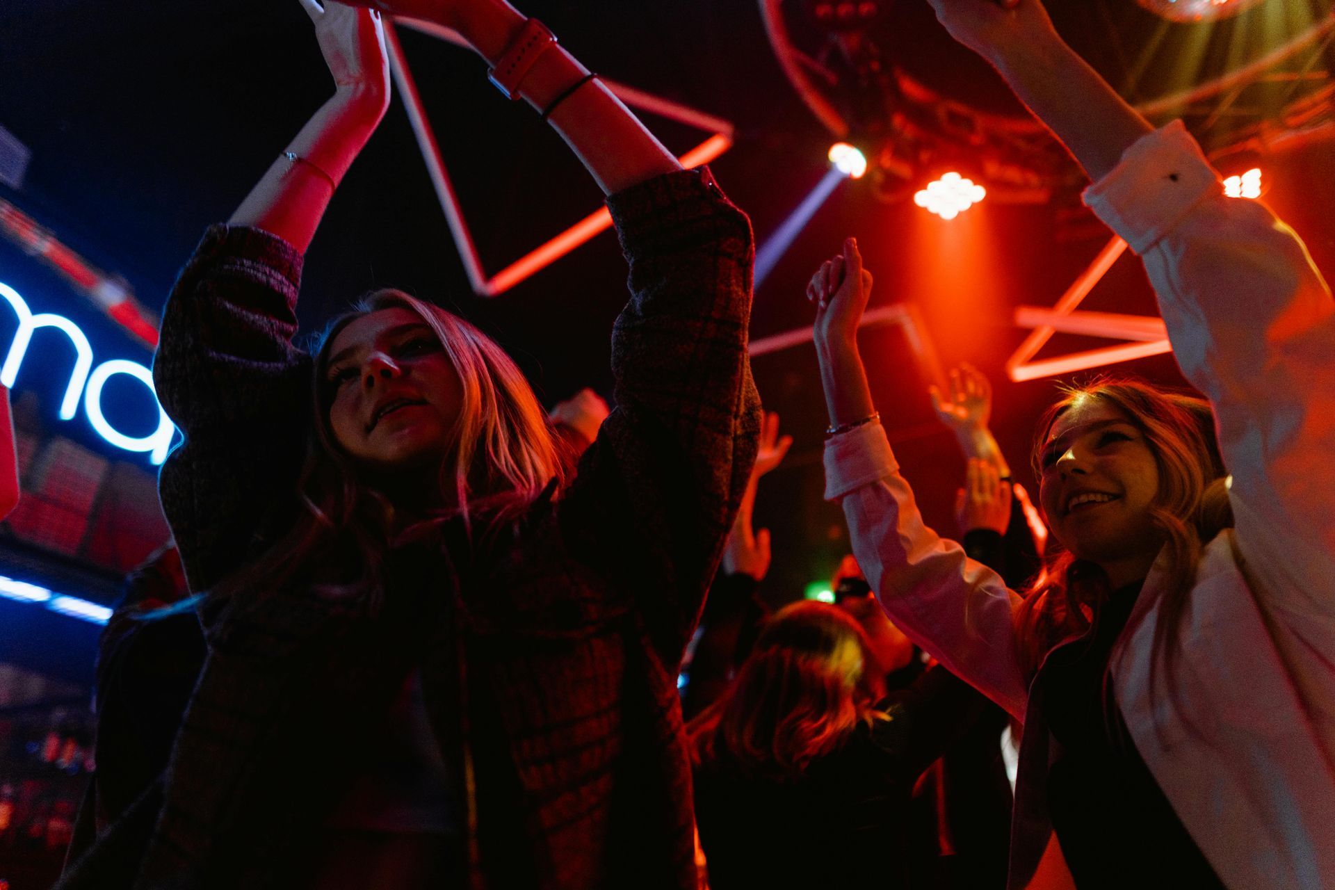 Un grupo de personas está bailando en un club con los brazos en el aire.