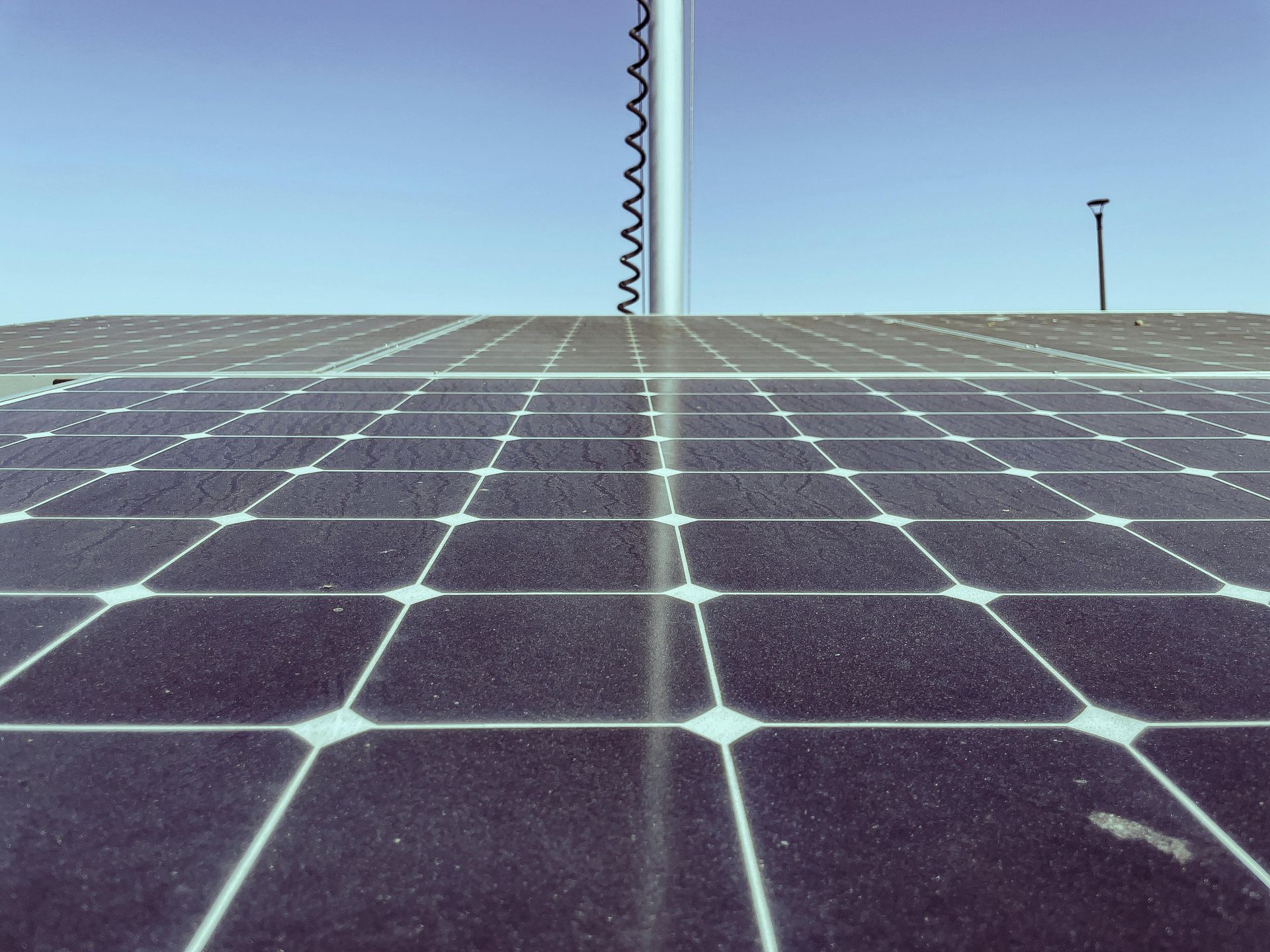 Una familia de tres sonríe mientras camina frente a un campo de paneles solares. El hombre lleva a un niño a hombros.