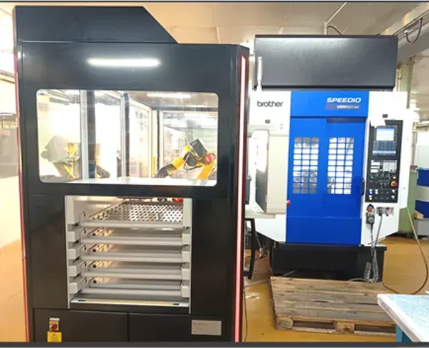 Machines CNC industrielles dans un atelier, une machine noire avec une fenêtre éclairée et une machine bleue et blanche en arrière-plan