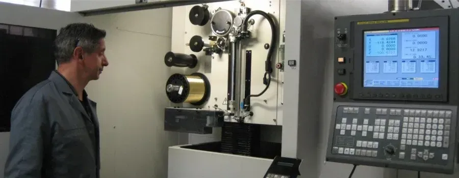 Un technicien inspecte une machine industrielle à côté d'un panneau de commande dans un atelier.