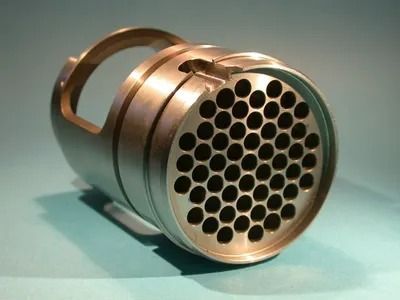 Objet cylindrique en métal argenté avec une poignée et une face avant percée de nombreux trous ronds sur une surface bleue