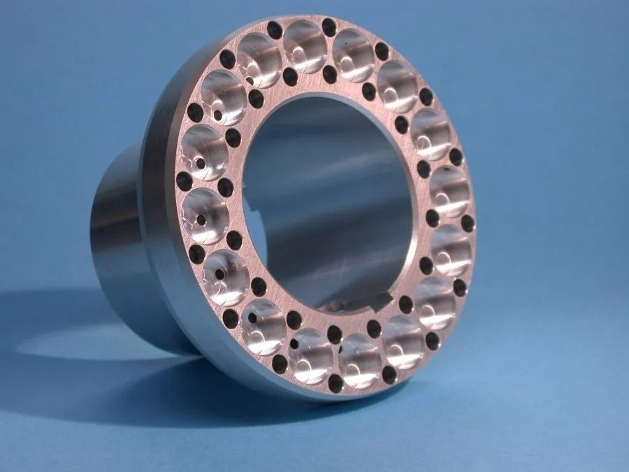 Anneau métallique percé de trous régulièrement espacés, sur fond bleu.