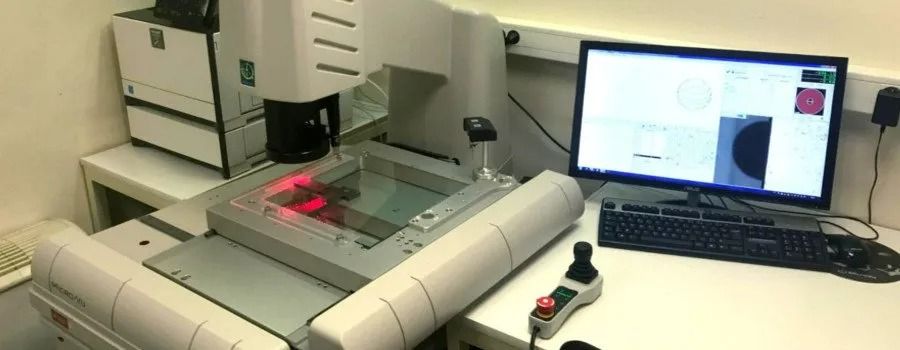 Poste de travail de laboratoire avec un scanner, un écran d'ordinateur et une souris sur un bureau blanc