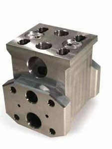 Bloc métallique usiné avec plusieurs trous percés, présenté en gros plan sur fond blanc