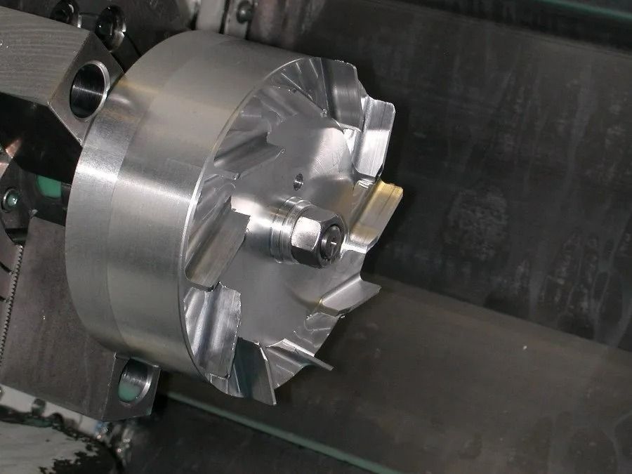 Mandrin de tour à métaux serrant une pièce usinée en argent dans un atelier.