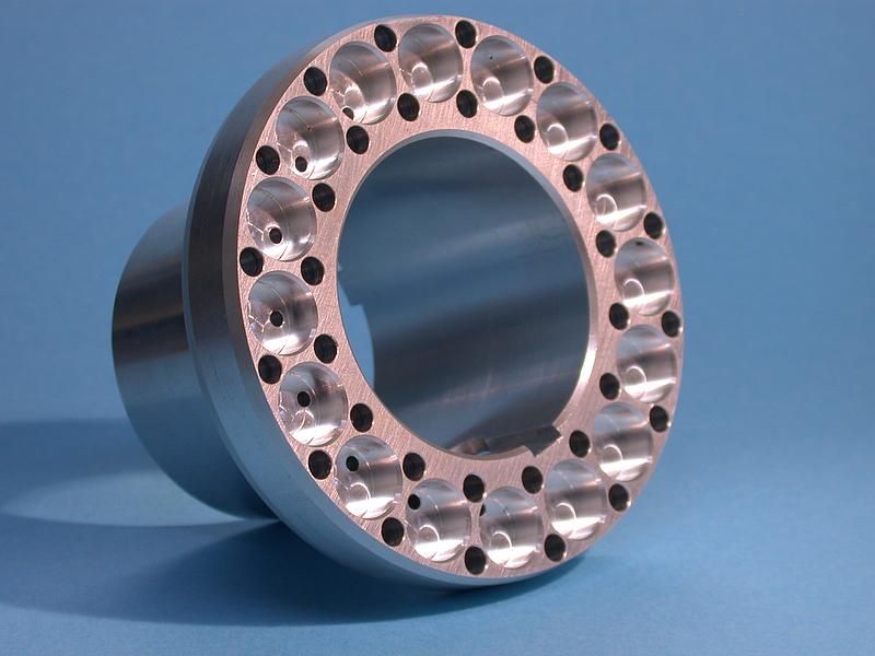 Pièce métallique circulaire usinée comportant de nombreux trous, représentée sur fond bleu